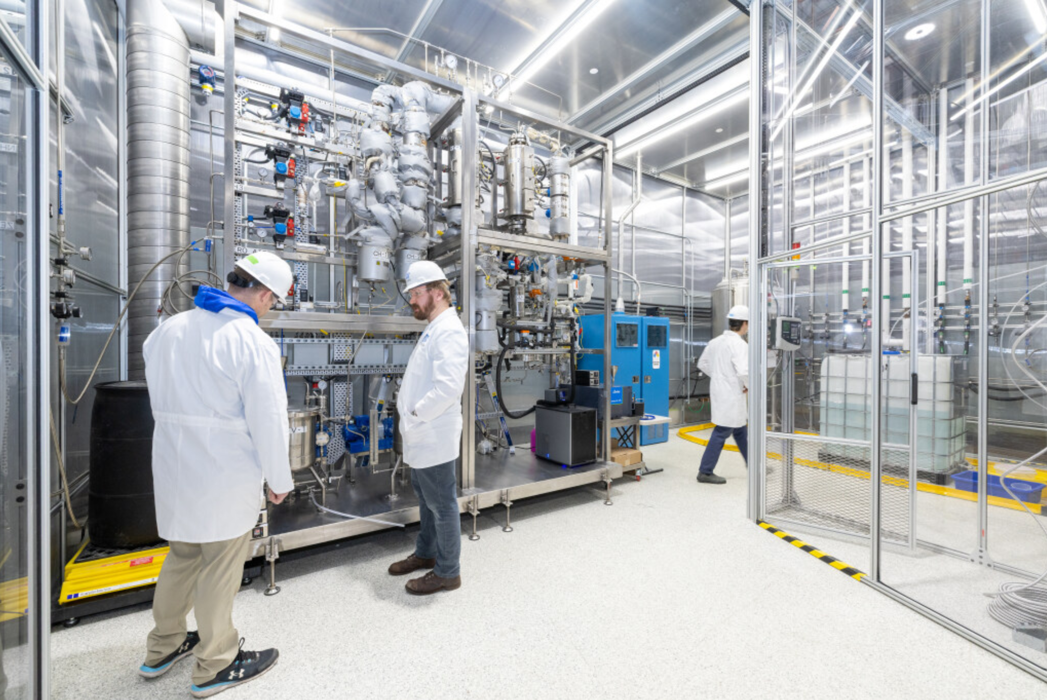 Safion team members reviewing pilot-scale processing equipment in a bright industrial setting