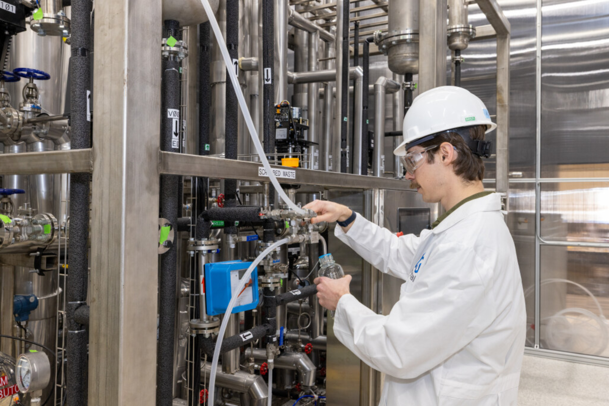 Scientist collecting a sample from stainless steel process equipment